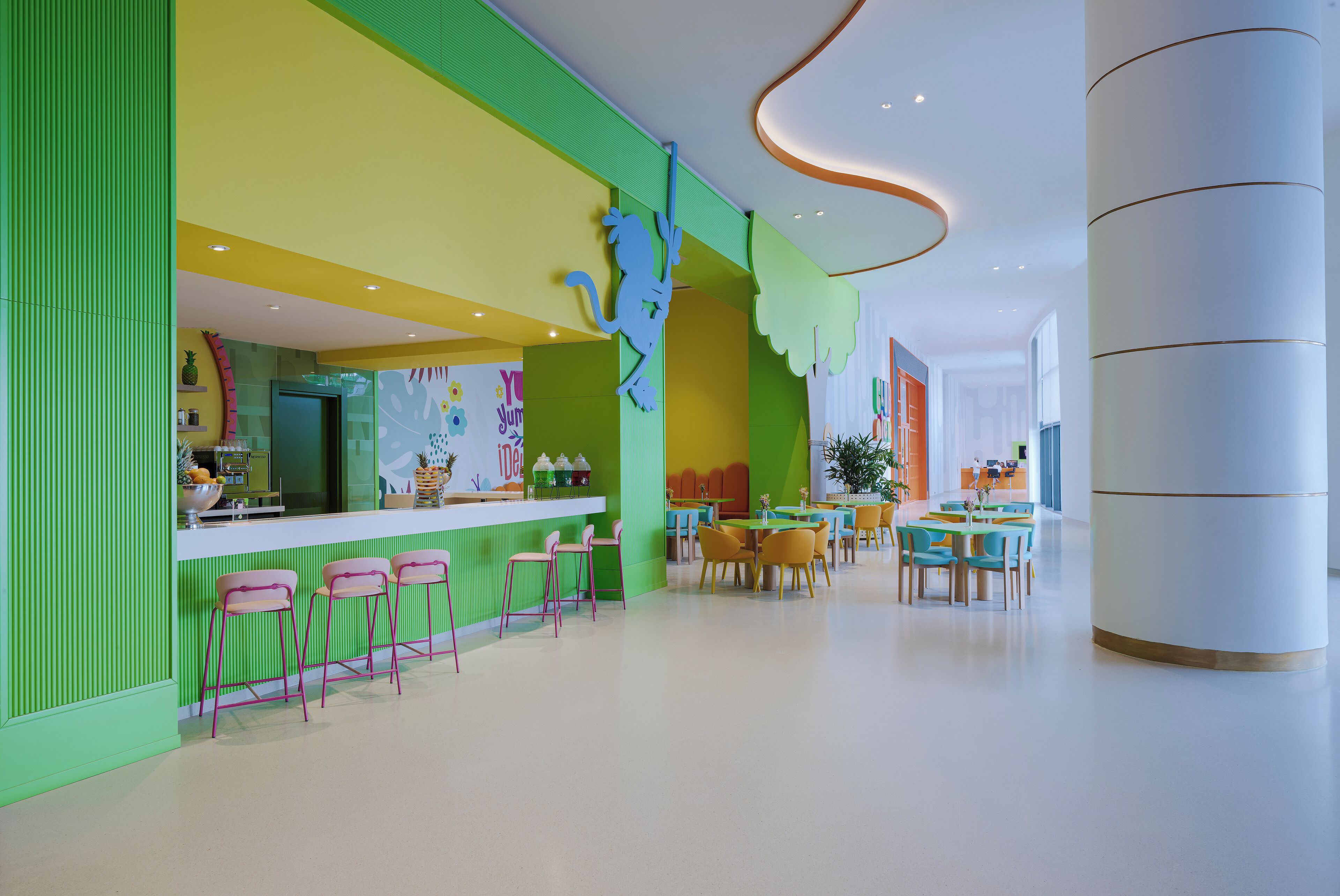 A brightly colored interior with a bar area, multiple seating arrangements, and a modern ceiling design.