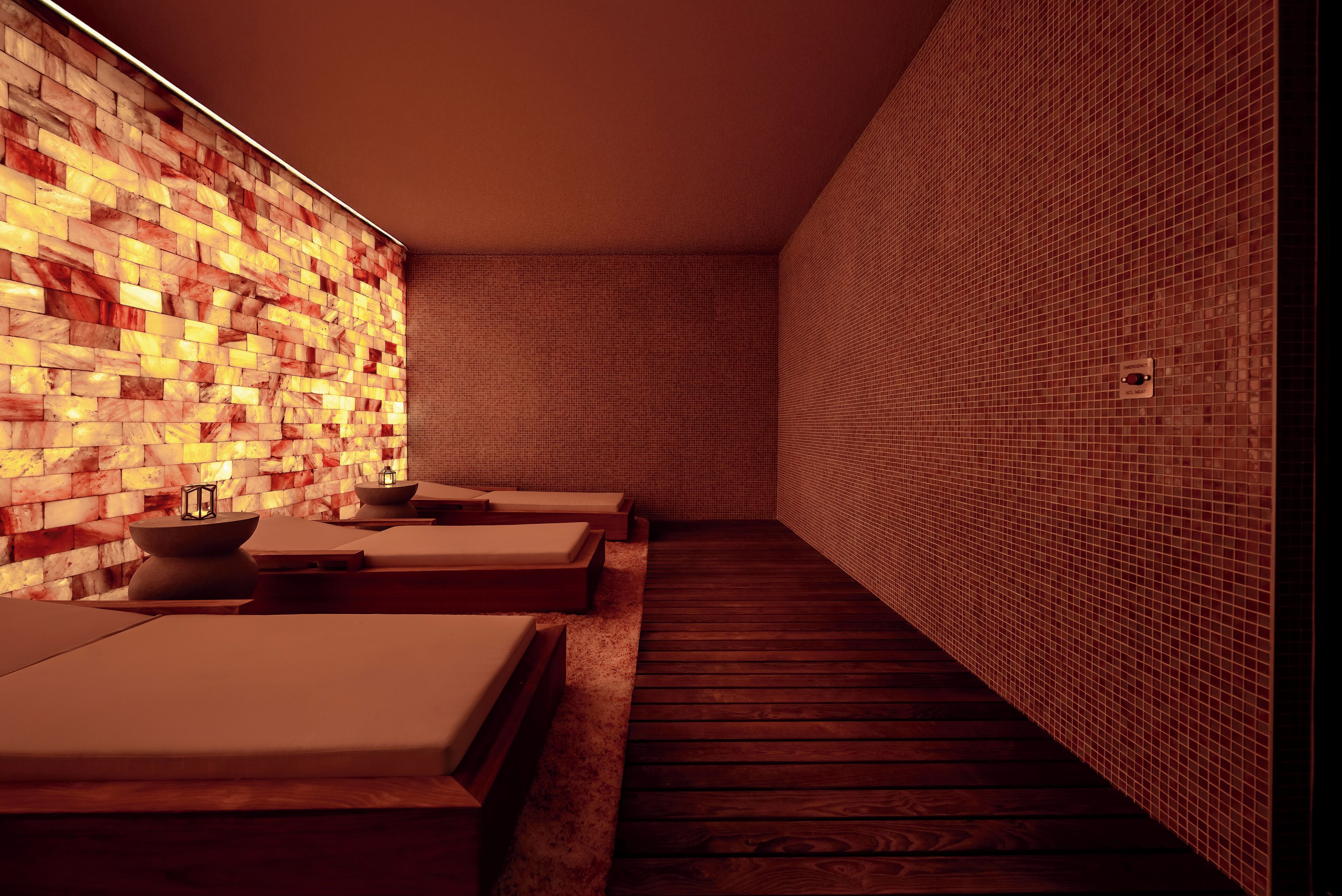 Un cuarto de spa con pisos de madera, paredes de azulejos y dos camillas de masaje con almohadones.