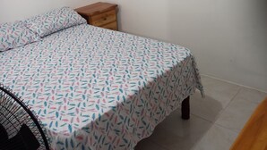 Une chambre à coucher avec un lit, une table de chevet, une affiche au mur et une chaise.