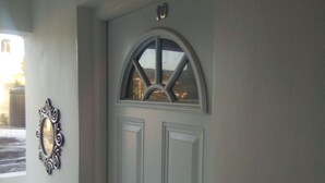 Une porte blanche surmontée d’un vitrail décoratif.