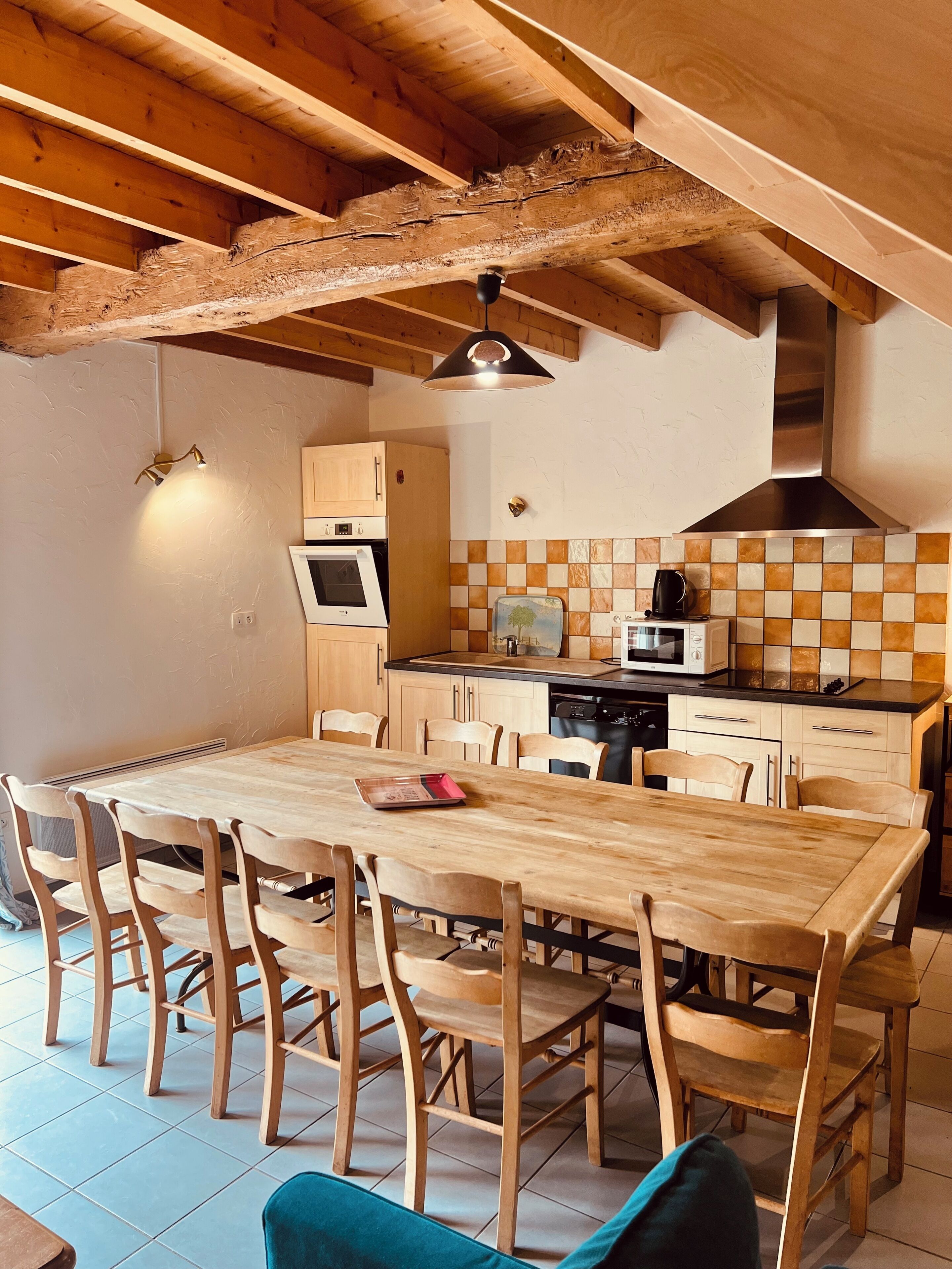 A kitchen with wooden cabinets, a dining table with chairs, and a tiled backsplash.