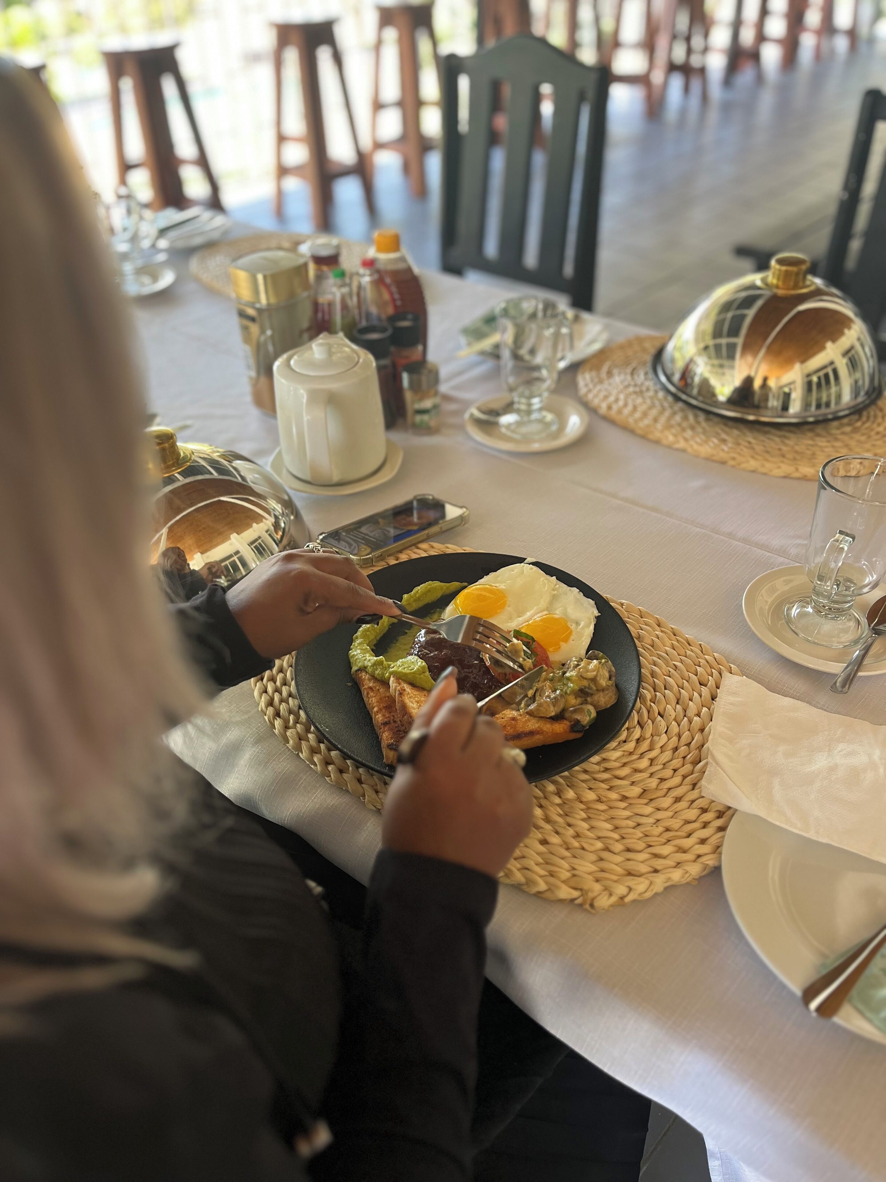 A dining table set with plates, cutlery, and a woven placemat.