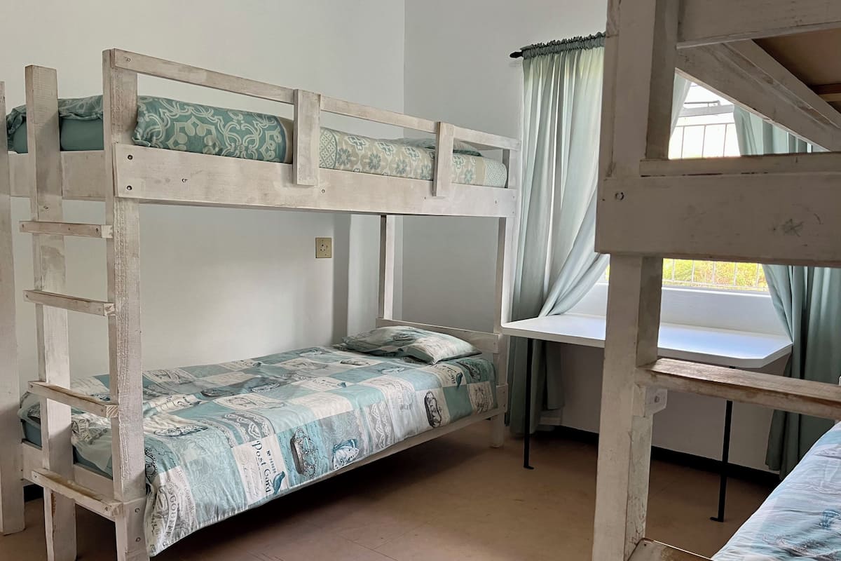 A bunk bed room with a window and curtains.