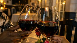Deux personnes trinquent avec des verres de vin autour d’une table sur laquelle on peut voir un panneau portant le chiffre « 10 », une bougie allumée, ainsi que des salières et des poivrières.