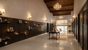 Un hall d’entrée spacieux, doté d’un plancher poli, de lambris en bois foncé, de luminaires fixés au mur et d’un lustre.