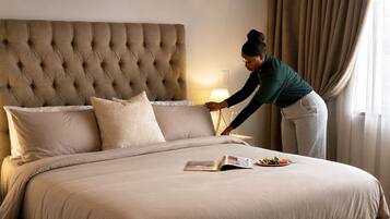 A neatly made bed with a tufted headboard, a bedside lamp, and a magazine on the bed.
