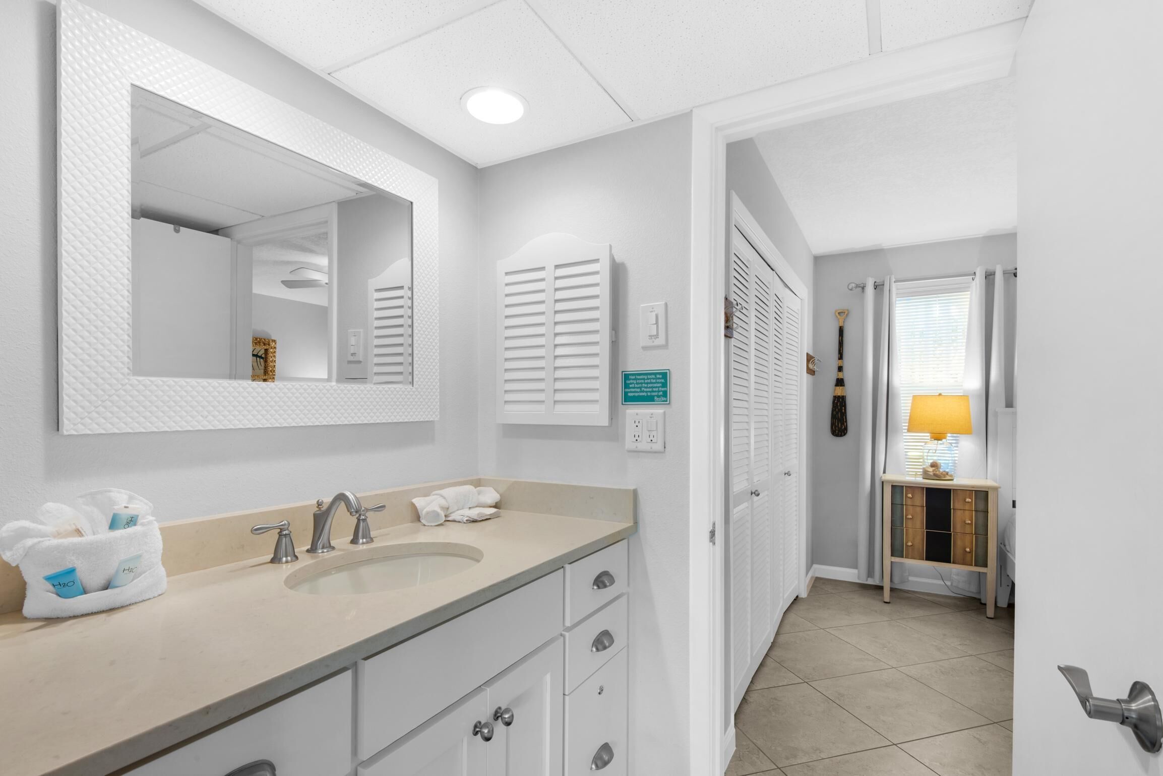 A bathroom with a large mirror, a sink, and a towel rack.