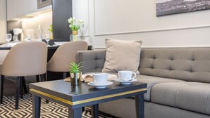 Ein modernes Wohnzimmer mit einer Couch, einem kleinen Tisch mit Tassen und einer Pflanze, sowie ein Essbereich mit Stühlen und einem Tisch.
