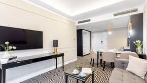 Ein modernes Hotelzimmer mit großem Flachbildfernseher, Essbereich und einer Sitzecke mit gemustertem Boden.
