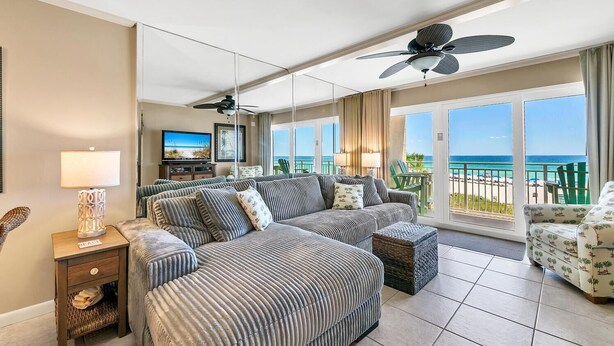 A spacious bedroom with a large bed, a seating area, and a balcony with a view of the ocean.