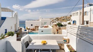 A white-walled building with a pool and a table with fruit.