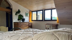 A bedroom with a large bed, a wooden dresser, a chair, and a desk. There is a window with curtains and a view of the outside. - 1 Bedroom Private vacation home in SoulignÃ©-sous-Ballon (Souligné-sous-Ballon)