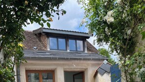 A small house with a tiled patio, a table with chairs, and potted plants. - 1 Bedroom Private vacation home in SoulignÃ©-sous-Ballon (Souligné-sous-Ballon)