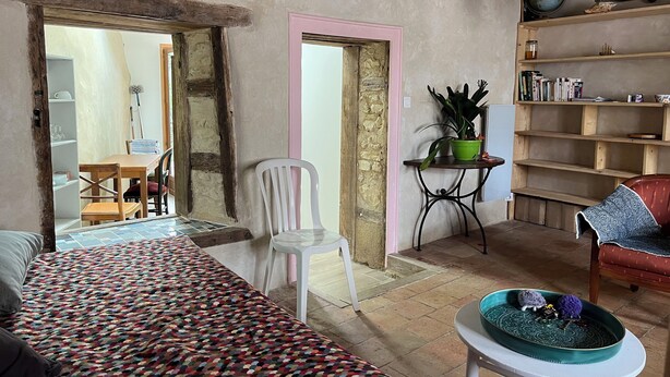 A cozy living room with a patterned sofa, a white chair, a small table with a decorative bowl, and a bookshelf with various items. - 1 Bedroom Private vacation home in SoulignÃ©-sous-Ballon (Souligné-sous-Ballon)