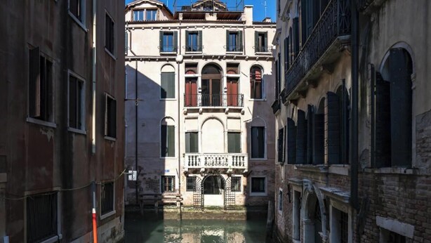 Un canal étroit, bordé de bâtiments des deux côtés, avec des balcons et des fenêtres en arc de cercle.