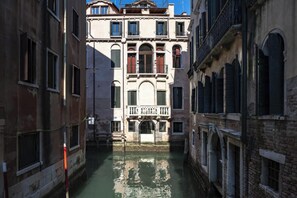 A narrow canal with buildings on either side, featuring balconies and arched windows.