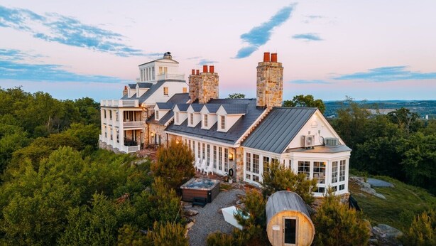 A large, multi-story house with a prominent chimney, a hot tub, and a small cabin-like structure. - Roundtop Mansion Breathtaking View indoor Pool (Wrightsville)