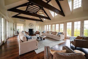 A spacious living room with a high ceiling, large windows, and a fireplace. - Roundtop Mansion Breathtaking View indoor Pool (Wrightsville)