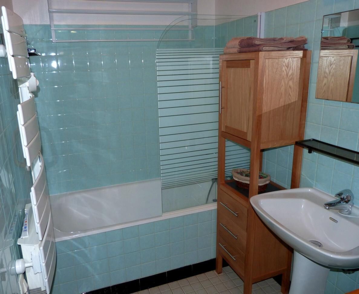 A bathroom with a bathtub, a sink, and a mirror.