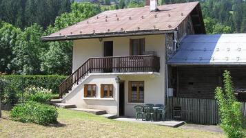 A two-story house with a balcony, a garage, and a small garden area.