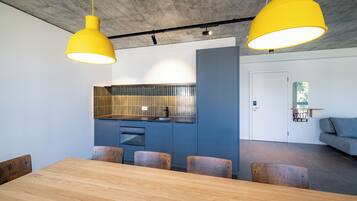 Una cocina moderna con armarios azules, una mesa de comedor de madera y dos lámparas colgantes amarillas.