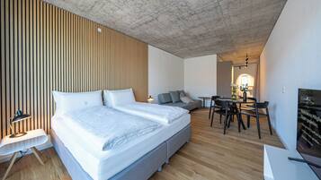 A modern bedroom with a large bed, a desk, and a sofa.