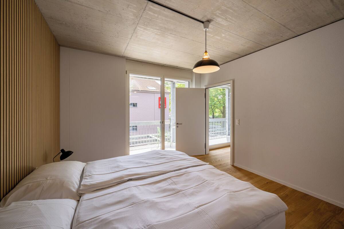 Un dormitorio con una cama, una lámpara en el techo y vistas al exterior.