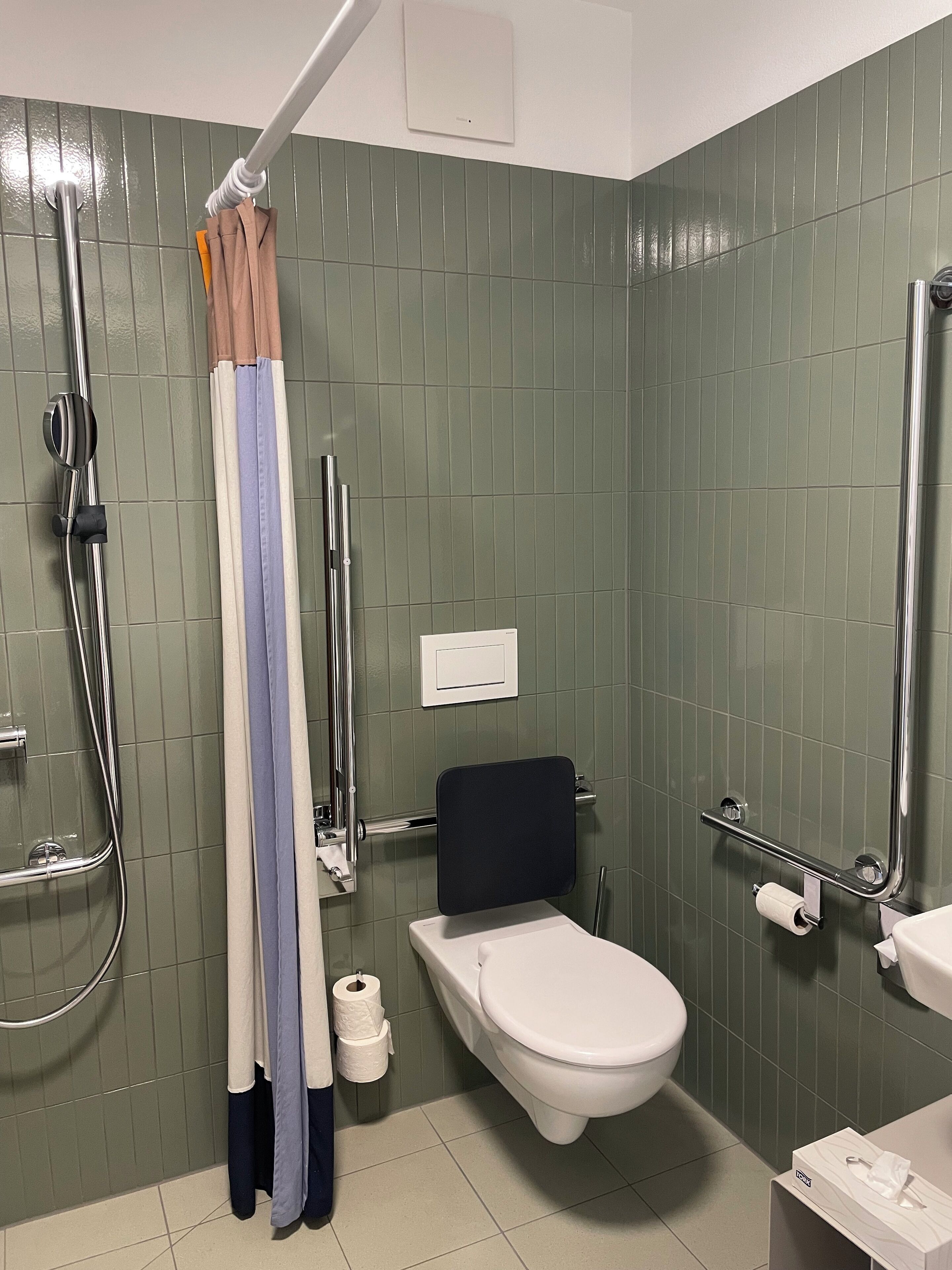 A bathroom with a toilet, a shower, and a sink.