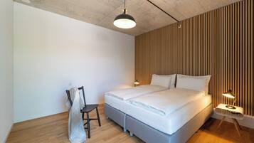 Ein modernes Schlafzimmer mit einem großen Bett, einem Sessel und einem Nachttisch mit Lampe.