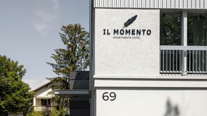 Un edificio con un letrero que dice "IL MOMENTO APARTMENTS HOTEL" y el número "69" en la fachada.