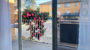 A balcony with a metal railing and a bush with pink flowers.