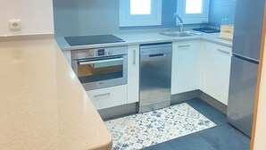 A modern kitchen with white cabinets, a Bosch oven, a dishwasher, and a stainless steel refrigerator. - Mikain Cathedral View (Donostia)