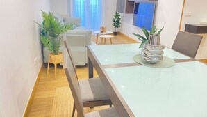 A modern living room with a glass dining table, grey sofas, and potted plants. - Mikain Cathedral View (Donostia)