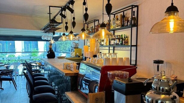 A bar area with a counter, stools, and a coffee machine. - EDWIN CAFE BAR PANSIYON (Ayvalik)