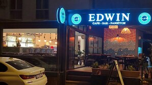 A cafe named 'Edwin' with a visible outdoor seating area and a car parked in front. - EDWIN CAFE BAR PANSIYON (Ayvalik)