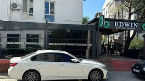 A white car parked in front of a building with a sign that reads "EDWIN CAFE - BAR - PANSYON". - EDWIN CAFE BAR PANSIYON (Ayvalik)