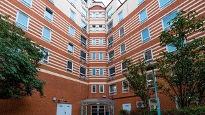 Een meerlaags bakstenen gebouw met een centrale binnenplaats, voorzien van een hekpoort en meerdere ramen.