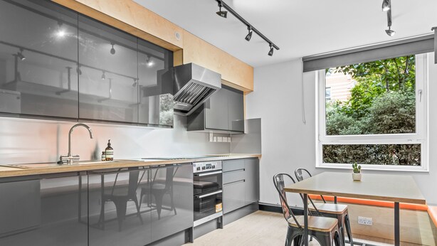 Een moderne keuken met een houten aanrecht, roestvrijstalen apparatuur en een eethoek met een tafel en stoelen.