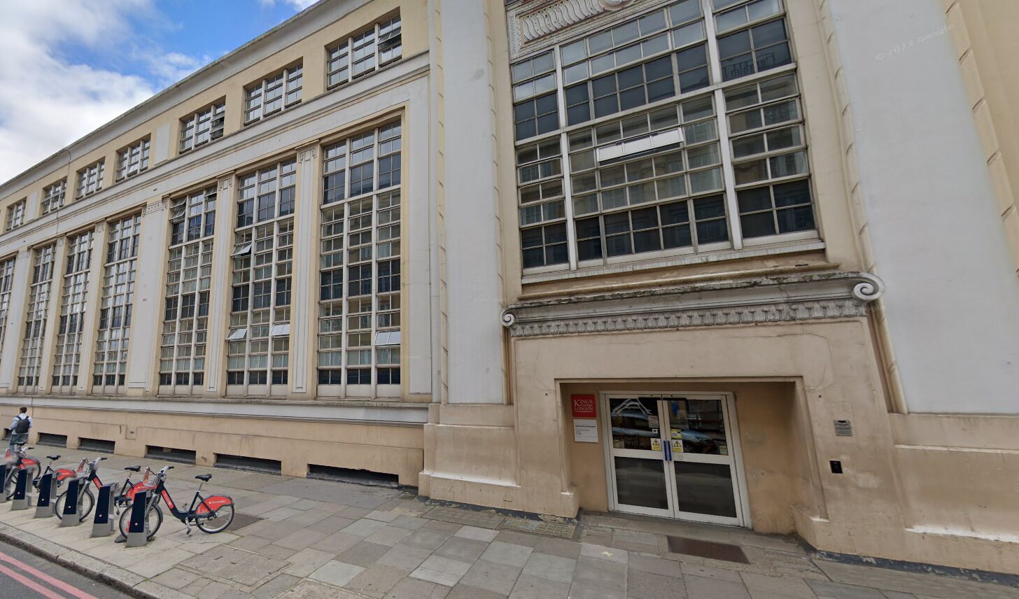 A building with large windows and a door with a sign. There are bicycles parked outside.