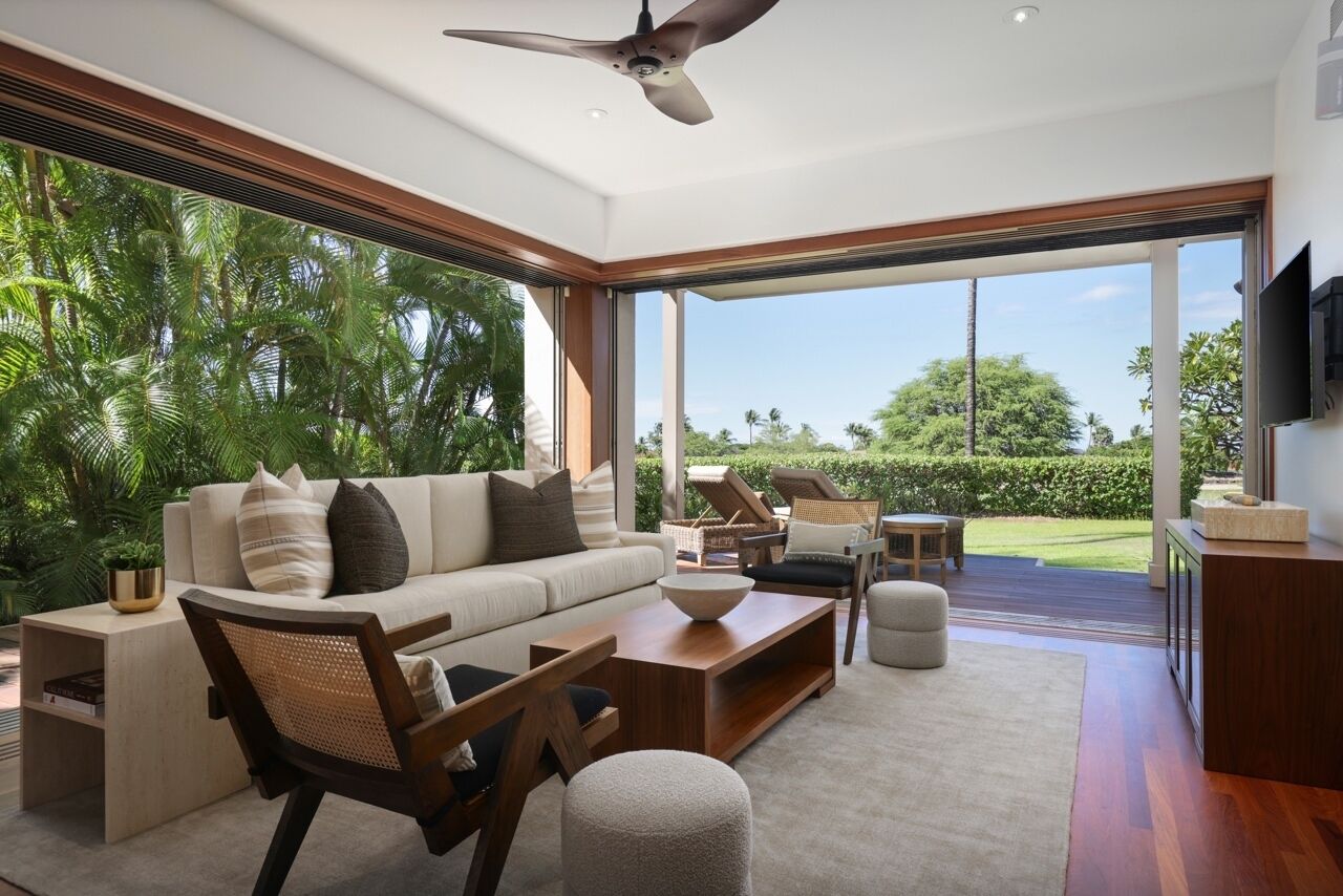 A modern living room with a large window, a ceiling fan, and a view of the outdoors.