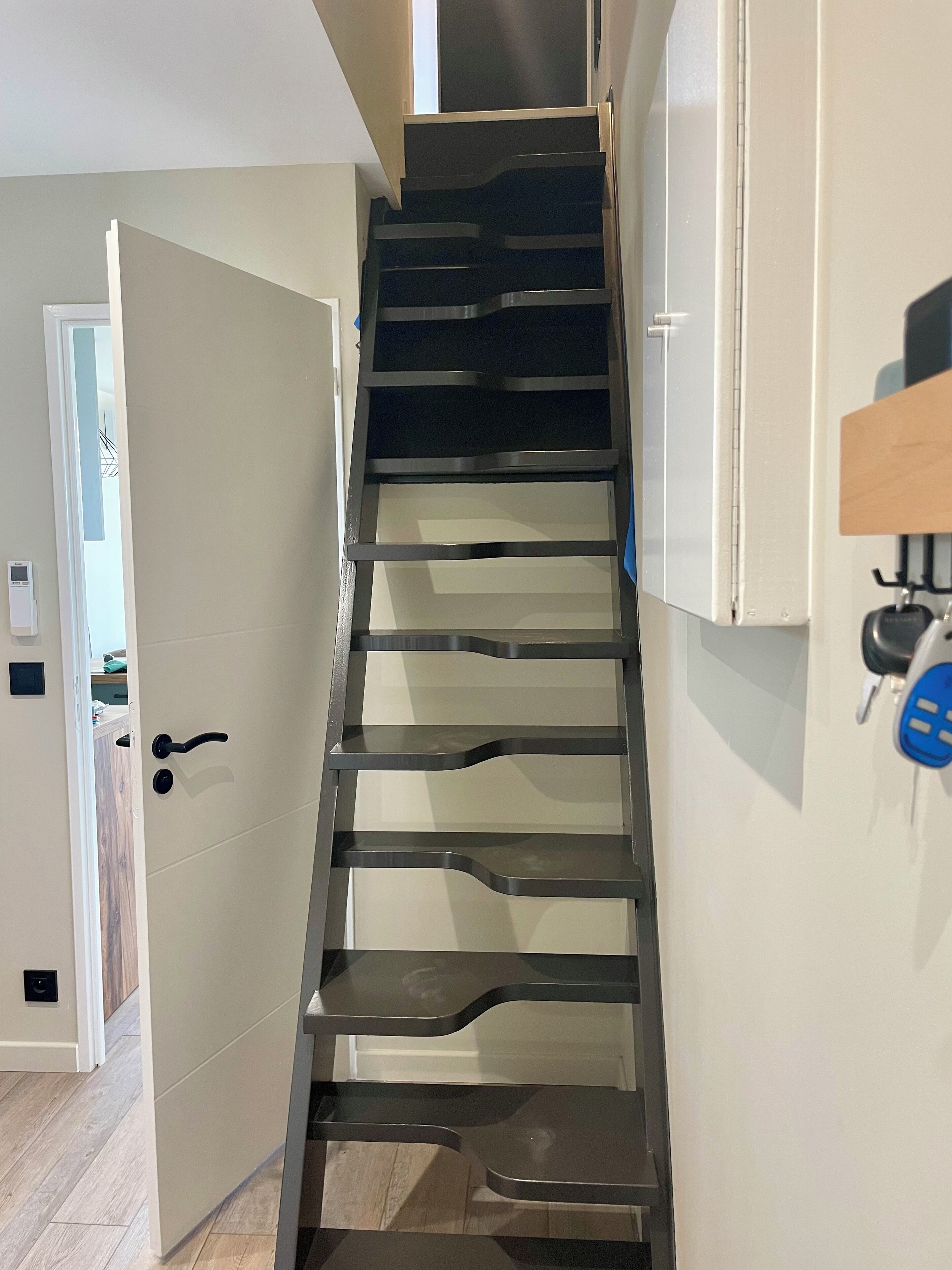 A narrow staircase with a door at the bottom leading to a room.