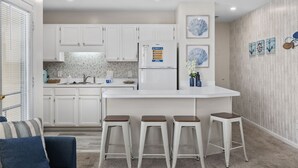 Een moderne keuken met witte kasten, een centraal kookeiland met krukken en decoratieve wandkunst.