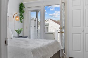 A bedroom with a bed, a nightstand, a wall-mounted lamp, and a view through a door. - Steps to Sand & NEW Surfside Pier!!-Top Floor-Parking-2 Private Balconies-  (Surfside Beach)