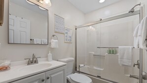 Een moderne badkamer met een douchecabine van glas, een witte wastafel en een toilet.