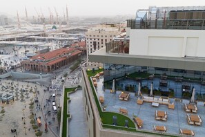 A rooftop terrace with outdoor seating and a view of a busy urban area. - Al Manakha Rotana Madinah (Madinah)