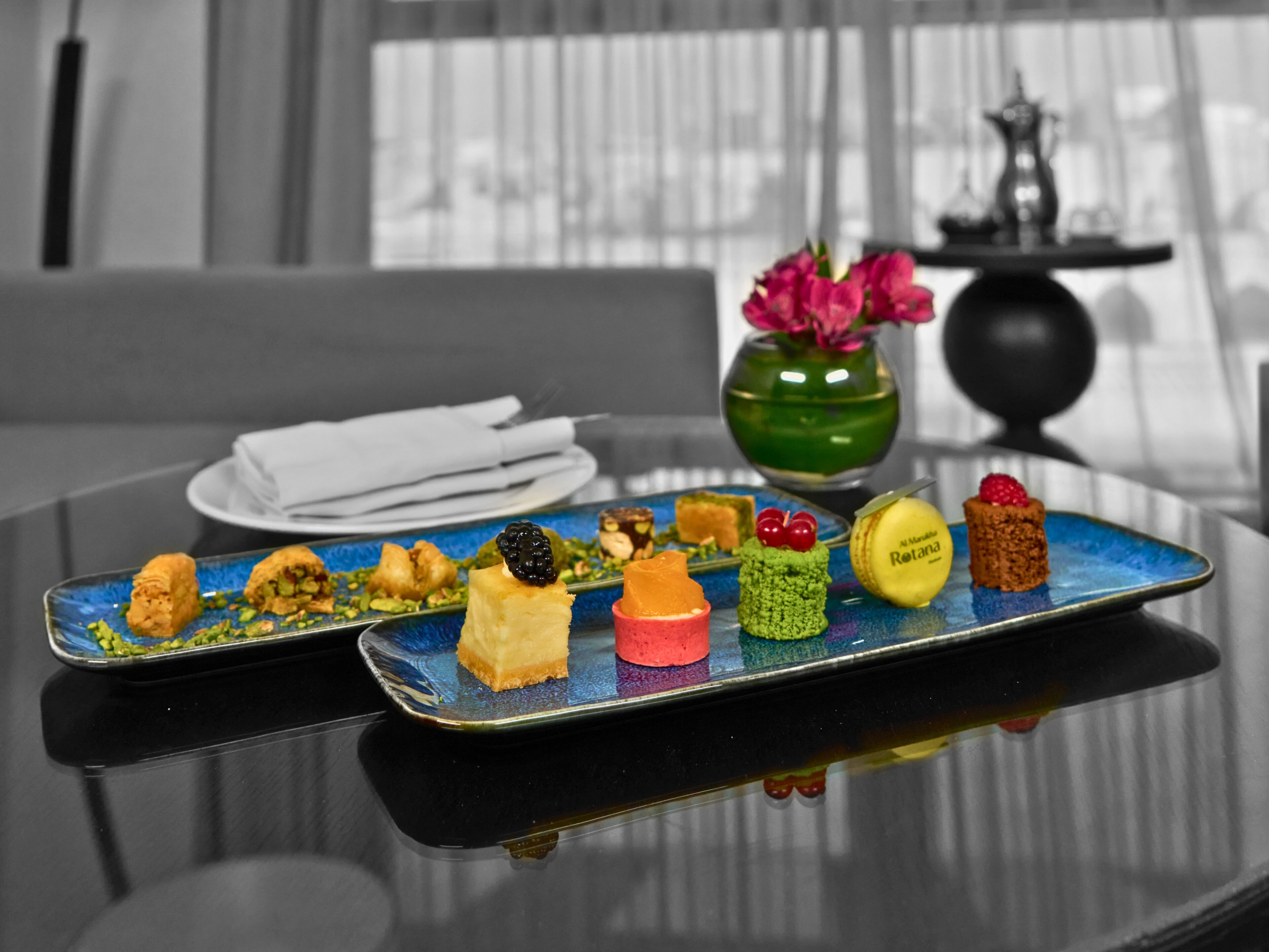 A dessert plate with various colorful sweets on a reflective surface.