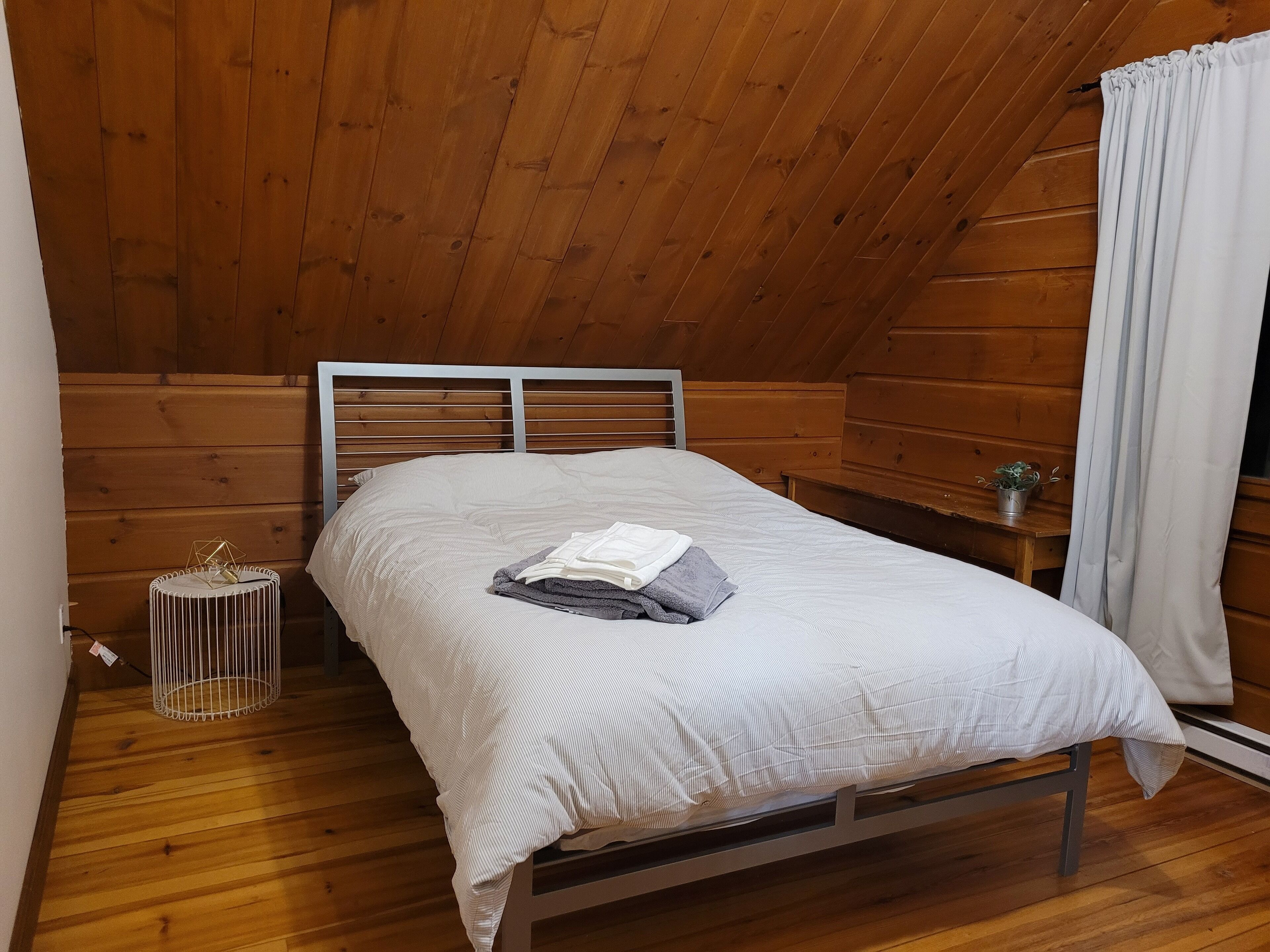 A single bed in a wooden room with a sloped ceiling.