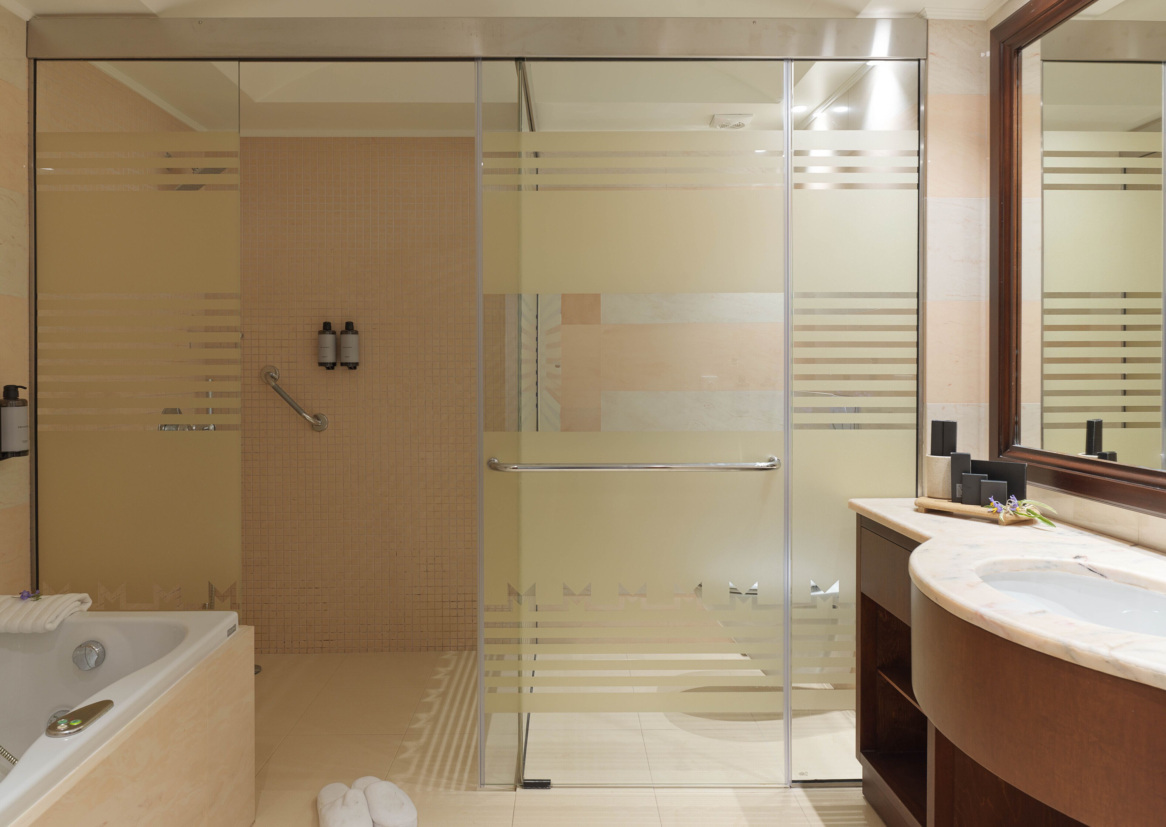 Een moderne badkamer met een douchecabine van glas, een badkuip en een wastafel met spiegel.