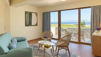 Een woonkamer met een bank, een tafel met fruit, rieten stoelen en uitzicht op zee.