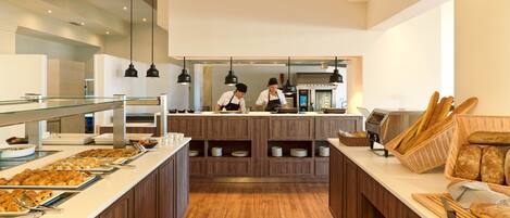 A buffet setup with various food items and a chef preparing food in the background.